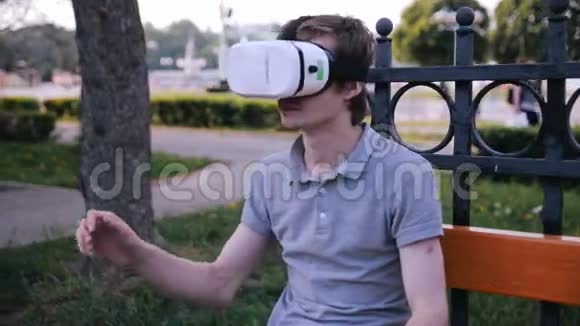 年轻的帅哥在城市公园里戴着虚拟现实护目镜视频的预览图