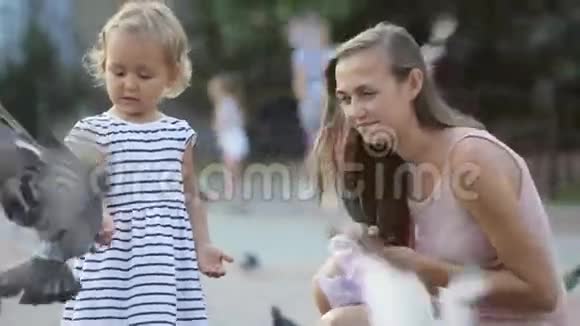 妈妈和小女孩在公园里喂鸽子视频的预览图