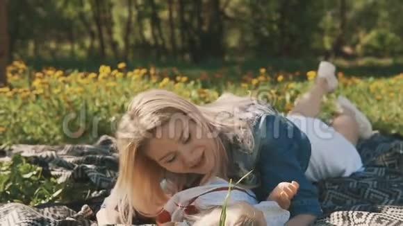 母亲和女儿躺在草坪上户外城市公园的家庭视频的预览图