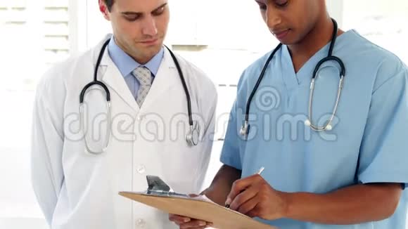 两名医务人员正在查看剪贴板上的档案视频的预览图