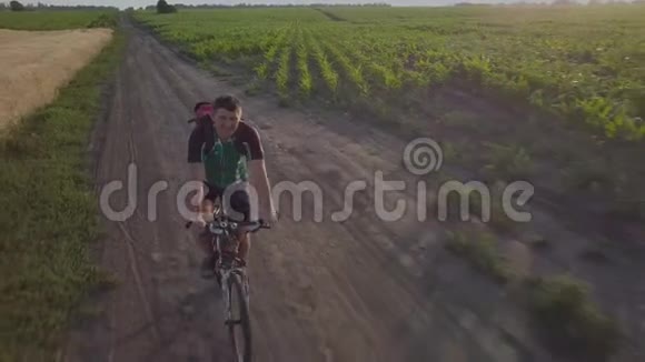 一个骑自行车的人沿着农田之间的道路骑车视频的预览图