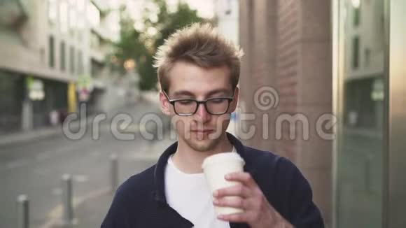 戴眼镜的男人喝着咖啡看着智能手机视频的预览图