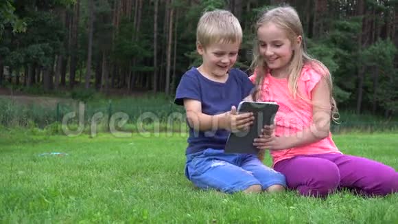 两个孩子在户外玩平板电脑视频的预览图