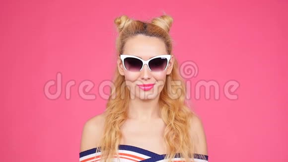带墨镜的粉色背景的年轻女子视频的预览图