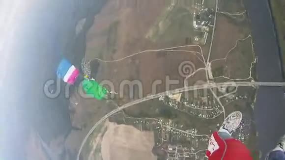 天空中的跳伞者飞过绿色的田野五颜六色的降落伞极限运动视频的预览图
