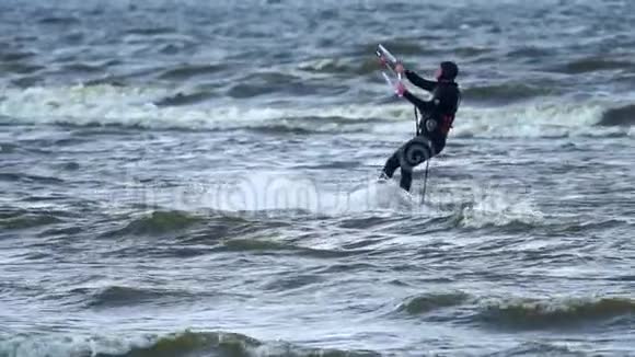 下情中年男子从事风筝活动他在湖面的波浪上美丽地骑着风筝强风视频的预览图