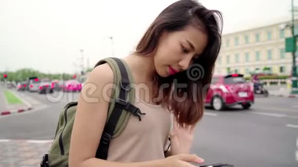 亚洲女游客背包客微笑使用智能手机独自旅行在曼谷的城市街道户外度假泰国视频的预览图