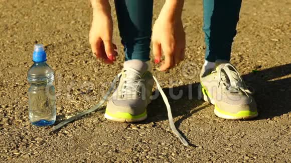 女孩停止跑步把鞋带系在跑鞋上健身女孩在户外训练高清120f视频的预览图