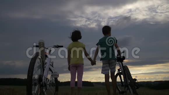 晚上男孩和骑自行车的女孩牵着手在山上视频的预览图