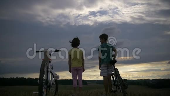 晚上男孩和骑自行车的女孩牵着手在山上视频的预览图