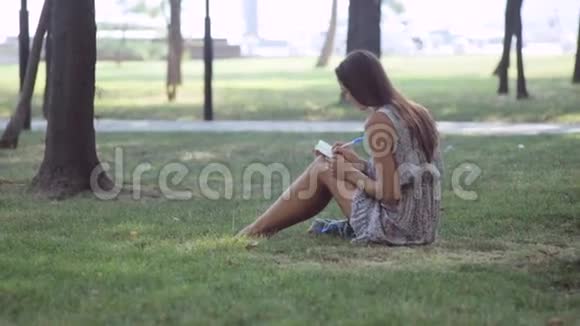 年轻女子在公园里写日记视频的预览图