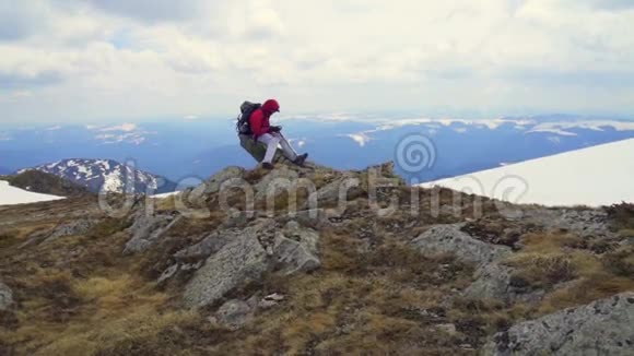 徒步旅行者坐在山景的岩石上视频的预览图