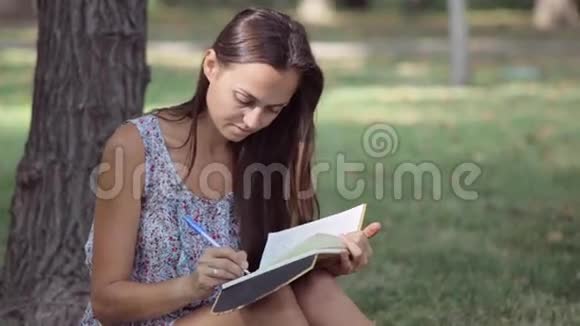 年轻女子在公园里写日记视频的预览图
