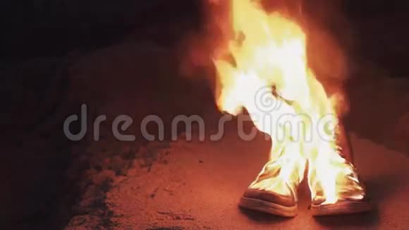 年轻人坐在海边沙滩上燃烧的鞋子篝火旁视频的预览图