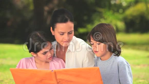 妈妈和孩子们在户外看一本书视频的预览图
