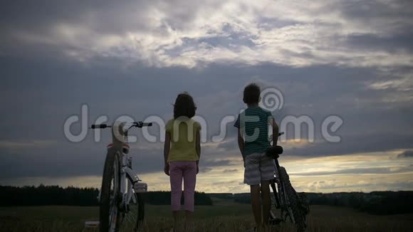 晚上带着自行车在山上的男孩和女孩视频的预览图