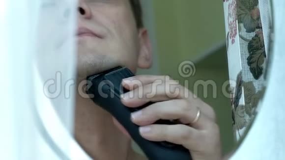 男人用电动剃须刀刮胡子检查剃须刀在脸颊上滑动手指特写镜头视频的预览图