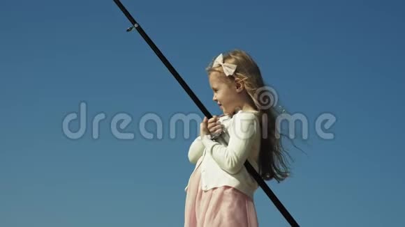 可爱的小女孩正在河边的渔船上玩鱼竿视频的预览图