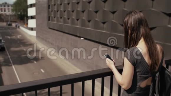 商务女性使用智能手机站在桥上俯瞰道路Stealicam拍摄慢节奏视频的预览图