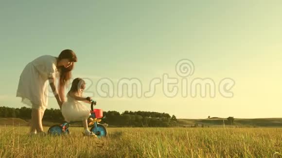 快乐妈妈教小女儿骑自行车妈妈在草坪上和小孩子玩孩子学会骑自行车视频的预览图