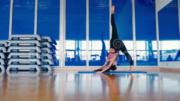 漂亮的女人在垫子上训练健身房的灵活性视频的预览图