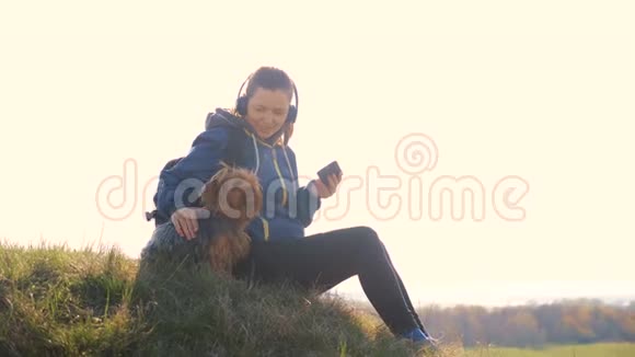 中年妇女和狗约克郡的游客带着背包在耳机里听音乐看着视频的预览图