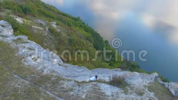 群山之间的湖上日落很大一对夫妇在悬崖边拥抱4k视频的预览图