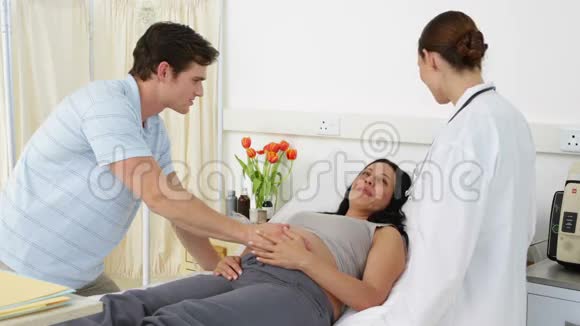 Brunette孕妇躺在床上与伴侣和医生交谈视频的预览图