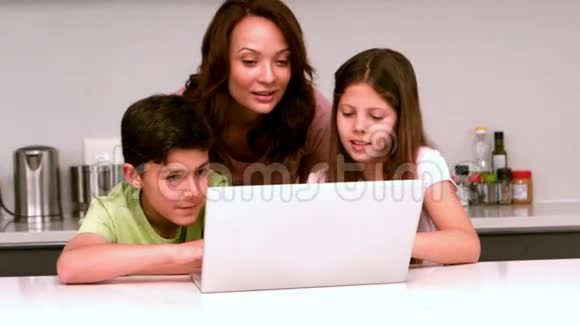 妈妈在厨房里和孩子们用笔记本电脑视频的预览图
