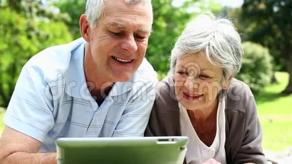 快乐的老两口在公园里用平板电脑放松视频的预览图
