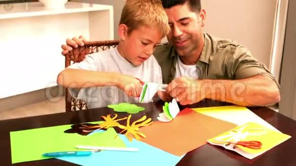 父亲和儿子一起在桌子上做纸形视频的预览图
