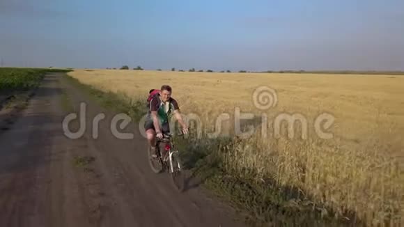 一个骑自行车的人沿着农田之间的道路骑车视频的预览图