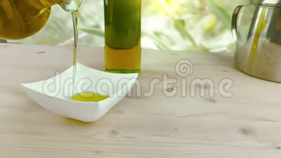在靠近橄榄油瓶的木桌背景上的白色容器中倒入食用油动作缓慢视频的预览图