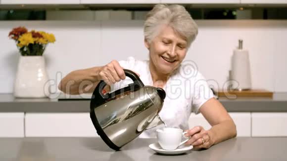 一位老年妇女从水壶里倒入开水视频的预览图