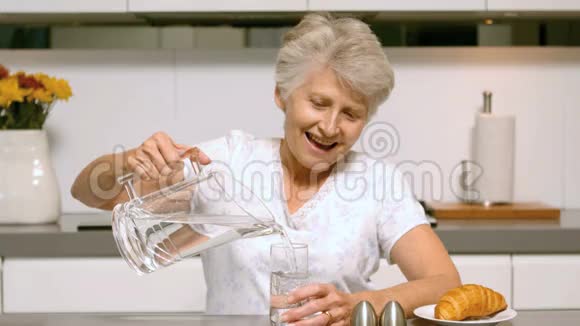 为早餐倒一杯水的老妇人视频的预览图