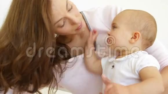 漂亮的年轻妈妈在床上和女婴玩耍视频的预览图