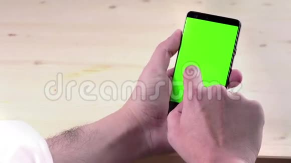 男人手使用智能手机木背景上带有色度键绿色屏幕生活方式交流视频的预览图