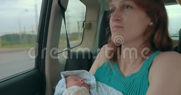 年轻的母亲在车里抱着新生儿视频的预览图