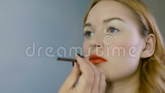 化妆大师的手画唇的年轻漂亮模特化妆正在进行中视频的预览图