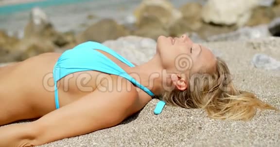 穿比基尼的金发女人躺在沙滩上视频的预览图