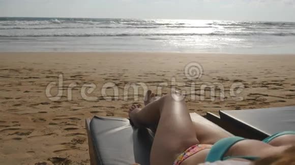 女性的身体在躺椅上在空荡荡的沙滩上放松和享受暑假年轻女子撒谎视频的预览图