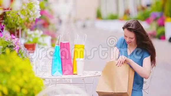 时尚快乐的女孩带着袋子购物后在露天咖啡馆喝咖啡销售消费主义和人的概念视频的预览图