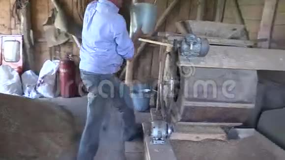 农夫用桶抽粮食倒入筛机视频的预览图