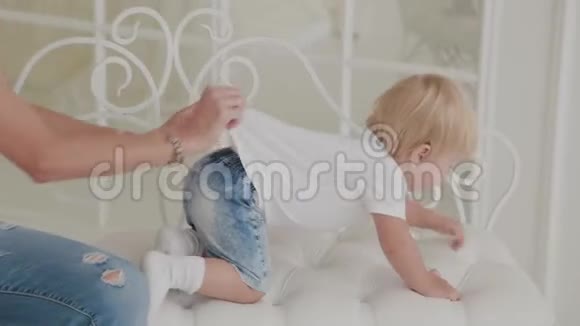 美丽快乐的妈妈和儿子正在白床上玩耍视频的预览图