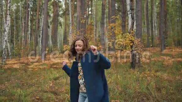 快乐的女孩跳舞在秋天的森林里玩得开心视频的预览图