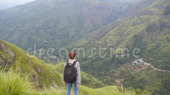 年轻的女徒步旅行者背包伸向山顶举起双手女游客站在视频的预览图