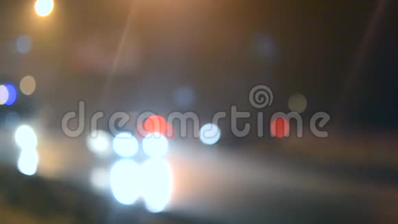 模糊的背景汽车在城市的一条潮湿的道路上行驶晚上视频的预览图