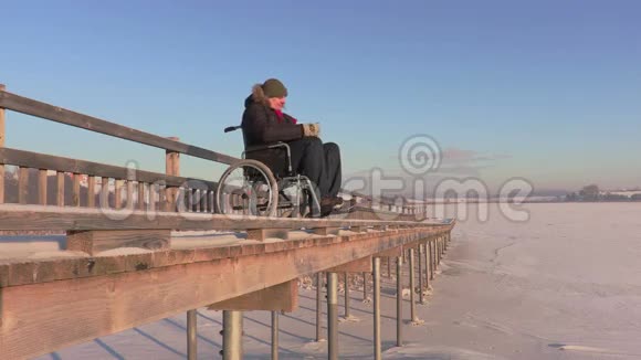 坐轮椅的残疾人在湖边的桥上用平板电脑视频的预览图