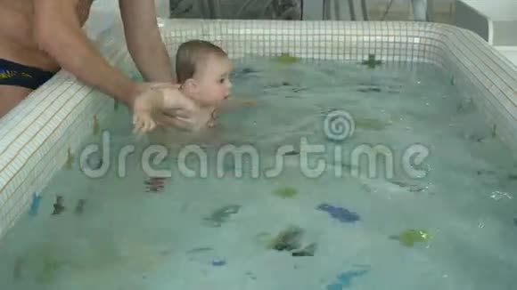 可爱的小孩和爸爸一起在游泳池里的水里游泳视频的预览图
