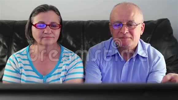 快乐的老年夫妇一起看电视视频的预览图